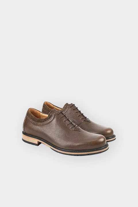 Un par de zapatos marrones de cuero con cordones y tacones bajos, representados sobre un fondo blanco.